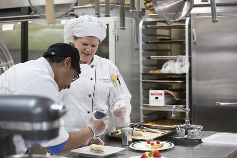 Culinary instructor helping student 
