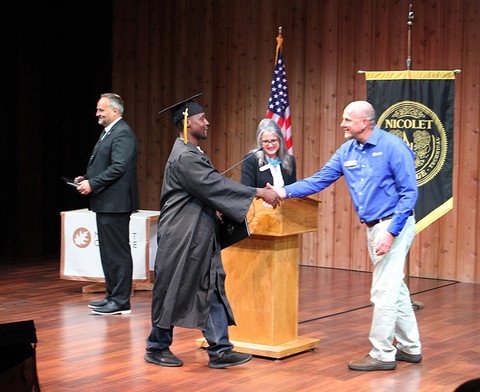 graduate walks across stage and shakes hand with instructor