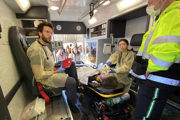 male and female students inside an ambulance performing health skills on a patient