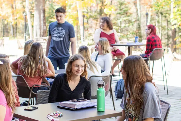 group of students sitting outside on lakeside patio talking and studying