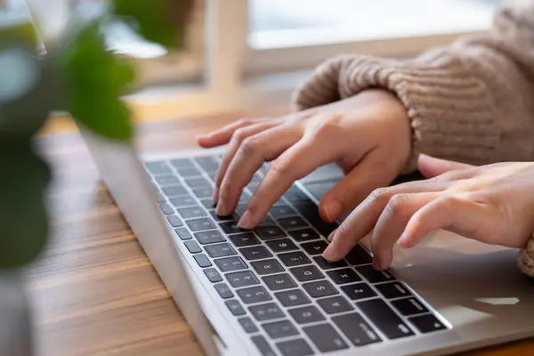 Hands typing on a laptop keyboard