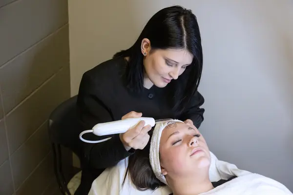 Esthetician performing a facial treatment on a relaxed client.