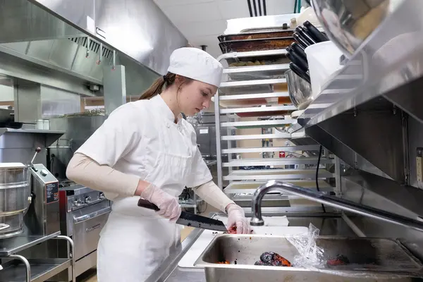 Young female student chef chopping vegetables.