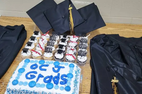 Graduation caps, gowns, cupcakes and cake displayed on a table.