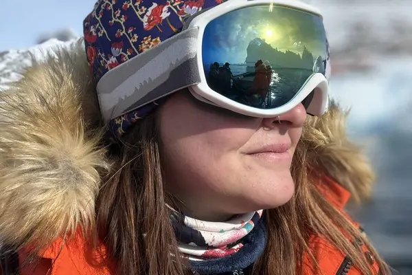 A woman in a winter coat, hat, and snow goggles.