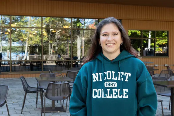 Female student smiling at the camera outside in a Nicolet College sweatshirt