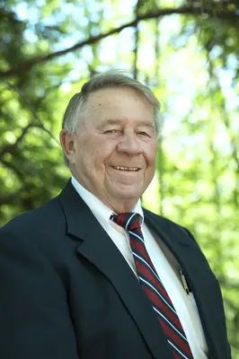 John Schiek, Nicolet College Foundation President smiling in suit and tie outdoors.
