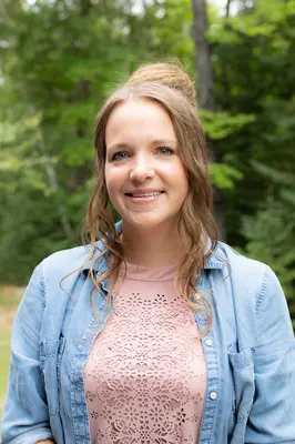 Smiling woman outdoors with trees in the background.