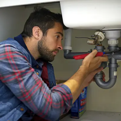 Plumber fixing piping under sink