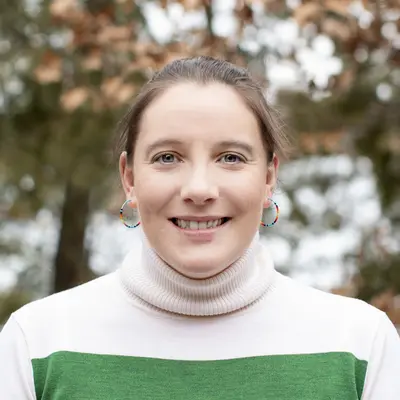 Smiling woman wearing a striped sweater outdoors in autumn.