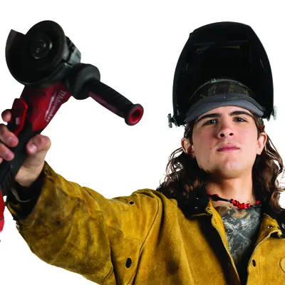Worker holding a power tool, wearing a welding mask and protective jacket.