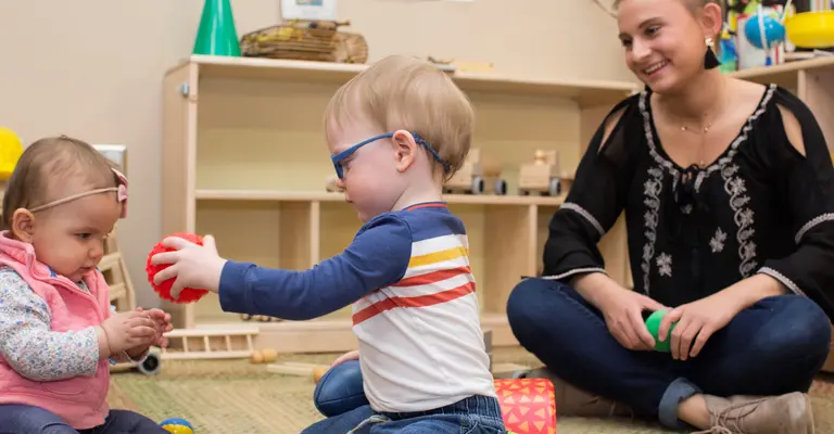 babies playing on floor with student teacher