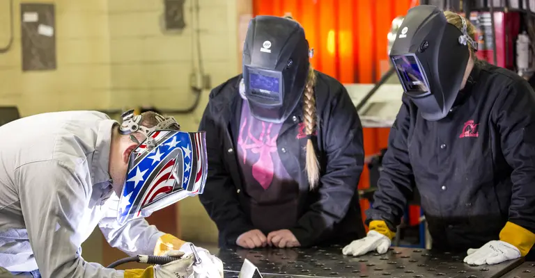 welding instructor showing students how to make a weld