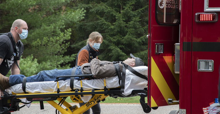 male emt loading a male patient on stretcher into ambulance as female emt looks on