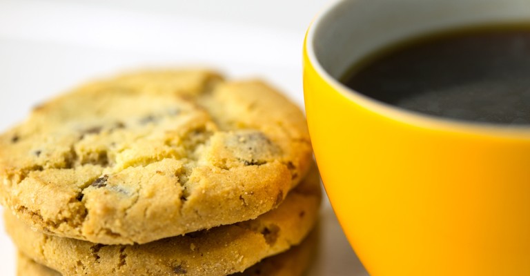 yellow coffee cup next to a stack of cookies