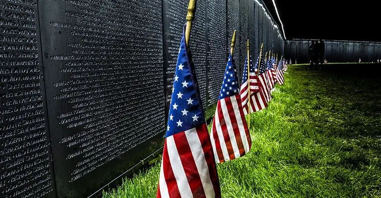 The wall that heals with american flags in front of it