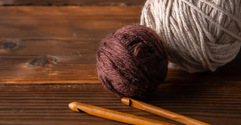 two balls of yarn with wooden knitting needles