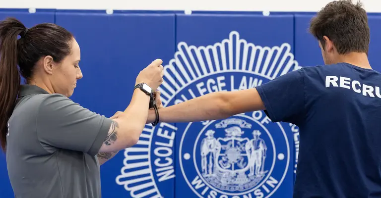 Instructor and trainee practicing defensive tactics in a gym.