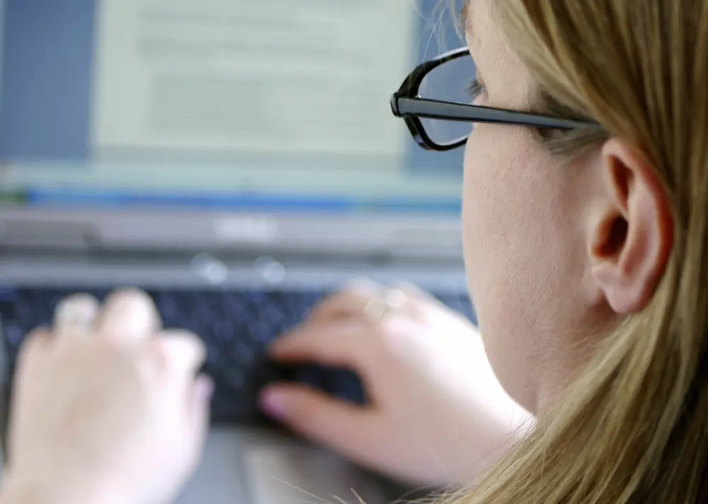 Close up of woman typing on a laptop, focusing on the screen.