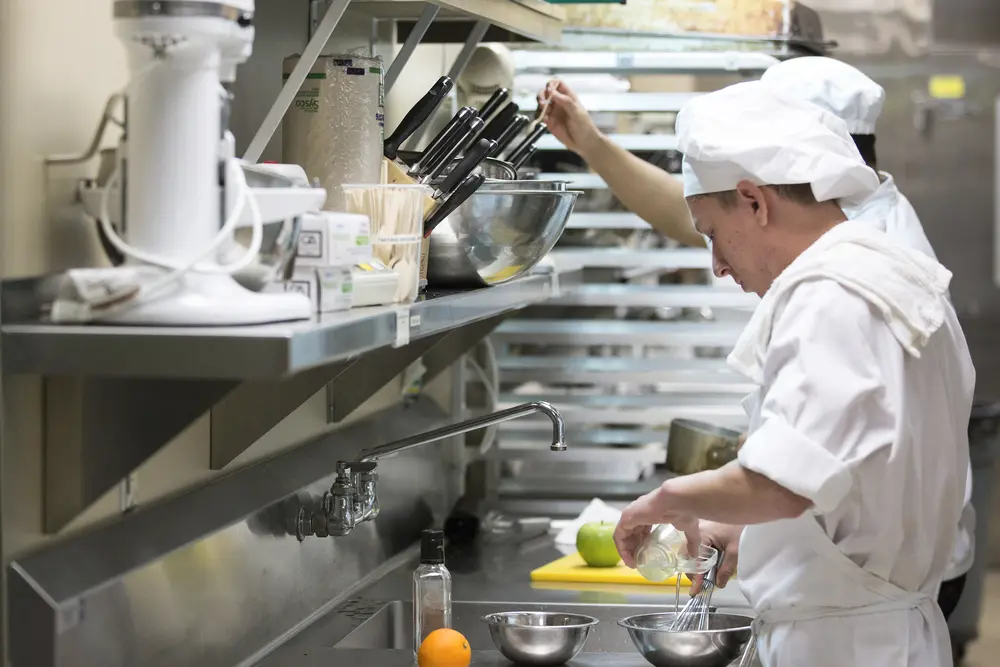 Culinary students in a busy kitchen preparing food.