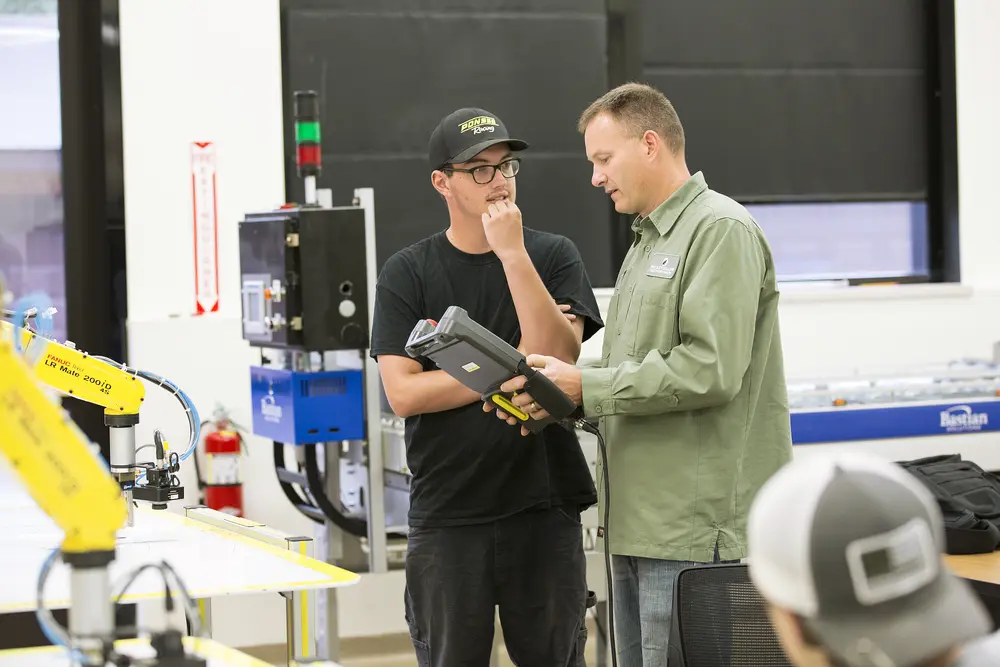 Electromechanical student talking with instructor in a workshop.