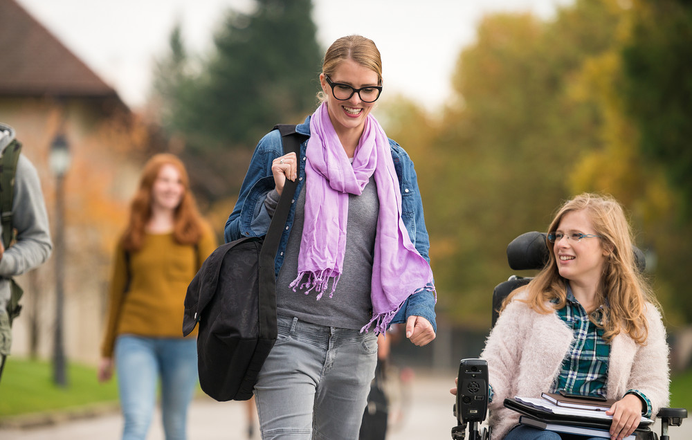 Girl walking and girl in wheelchair on campus