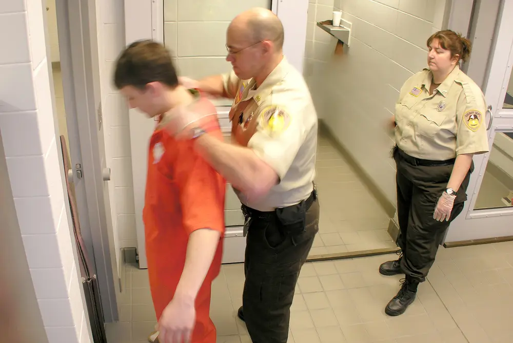 Students and instructor training for jail academy, two as officers and one as inmate being searched.