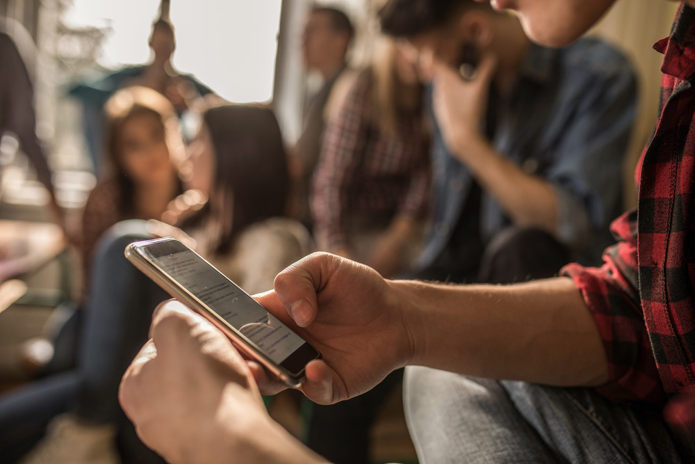 Student in a crowd holding cell phone