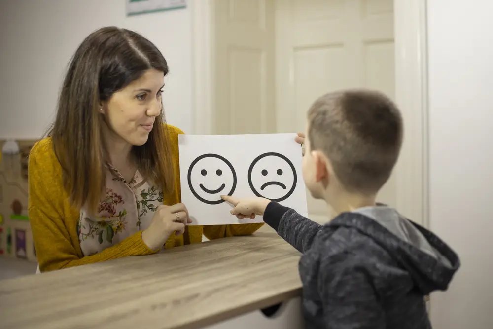 Woman and child discussing smiley and sad face drawings.