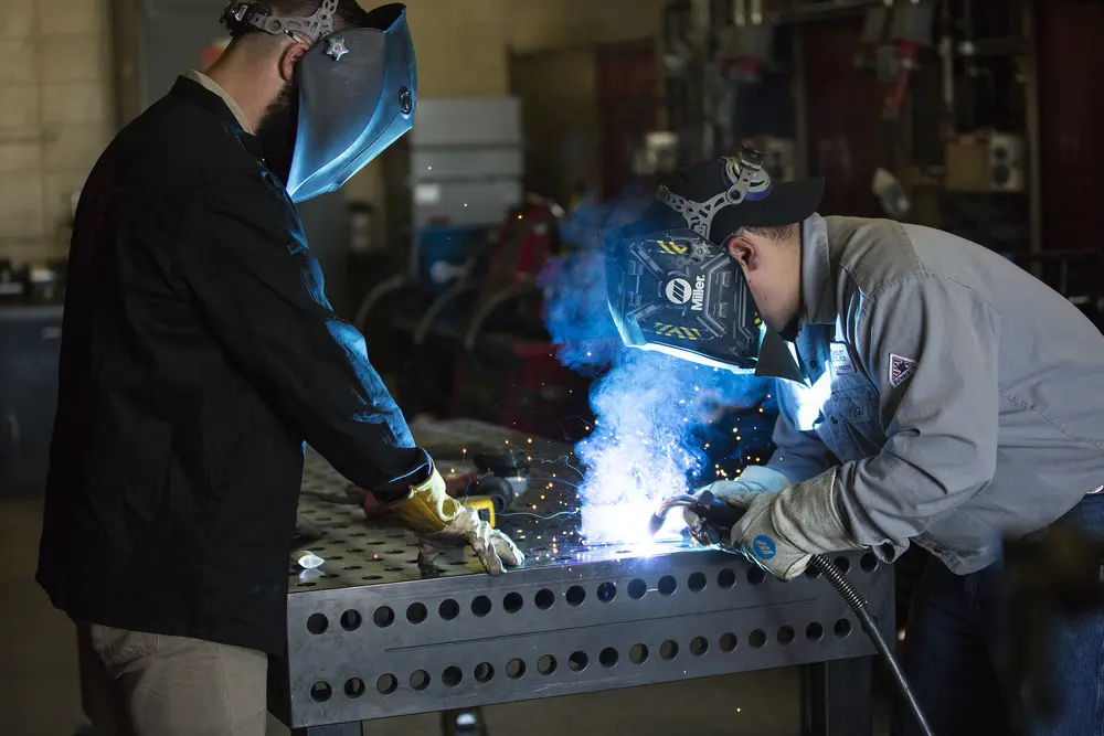 Welding instructor helping student