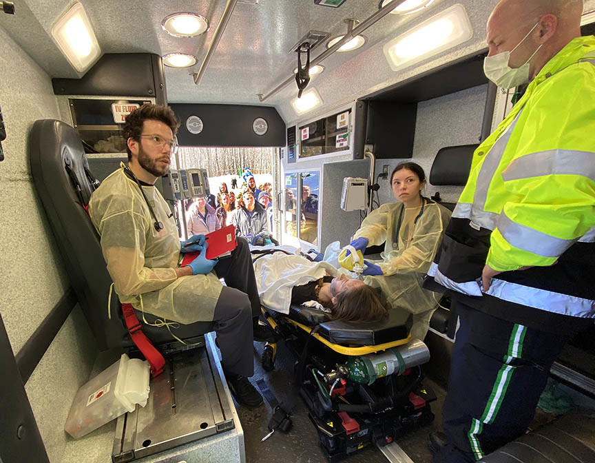 male and female students inside an ambulance performing health skills on a patient