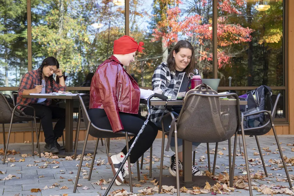 female students sitting outside in fall studying