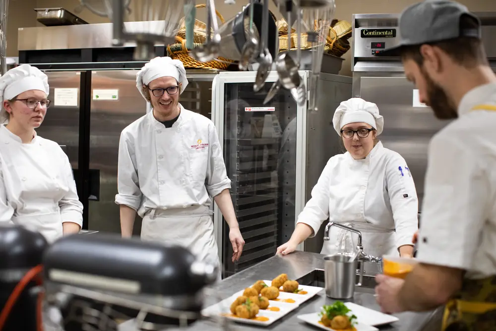 Instructor Chef Mitch working with a group of culinary students in the kitchen