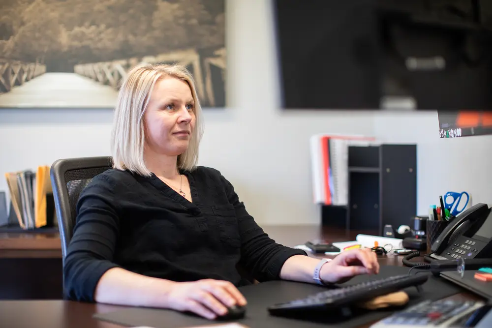 Woman at desk working on a computer, office setting.