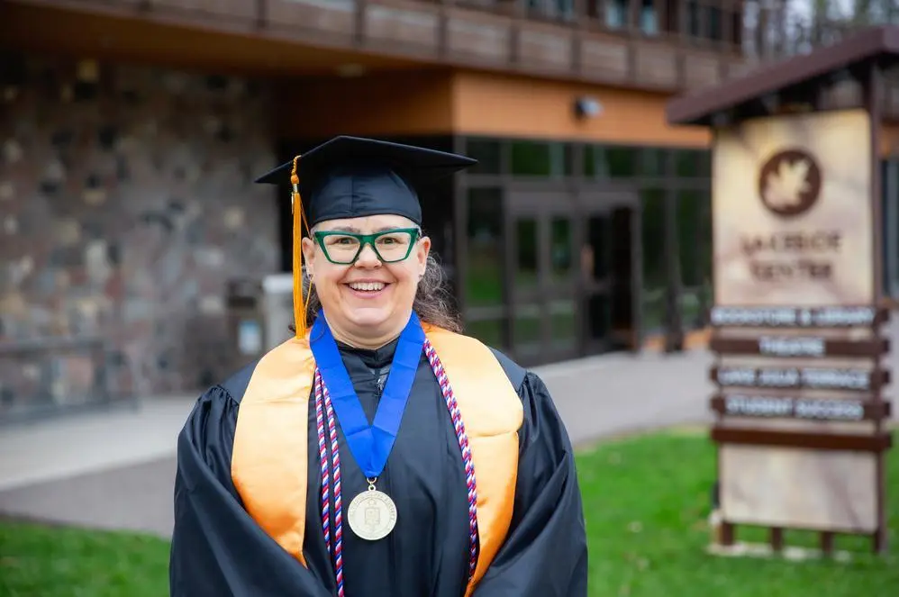 A person in graduation regalia, smiling.