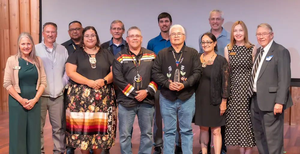 Group of people smiling on stage in formal and casual attire.