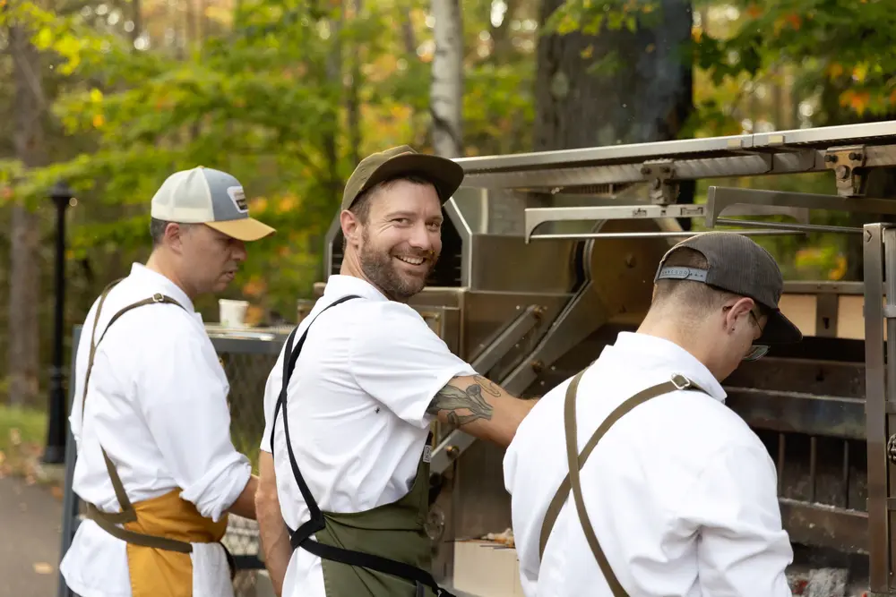 Chefs cooking on an outdoor grill.