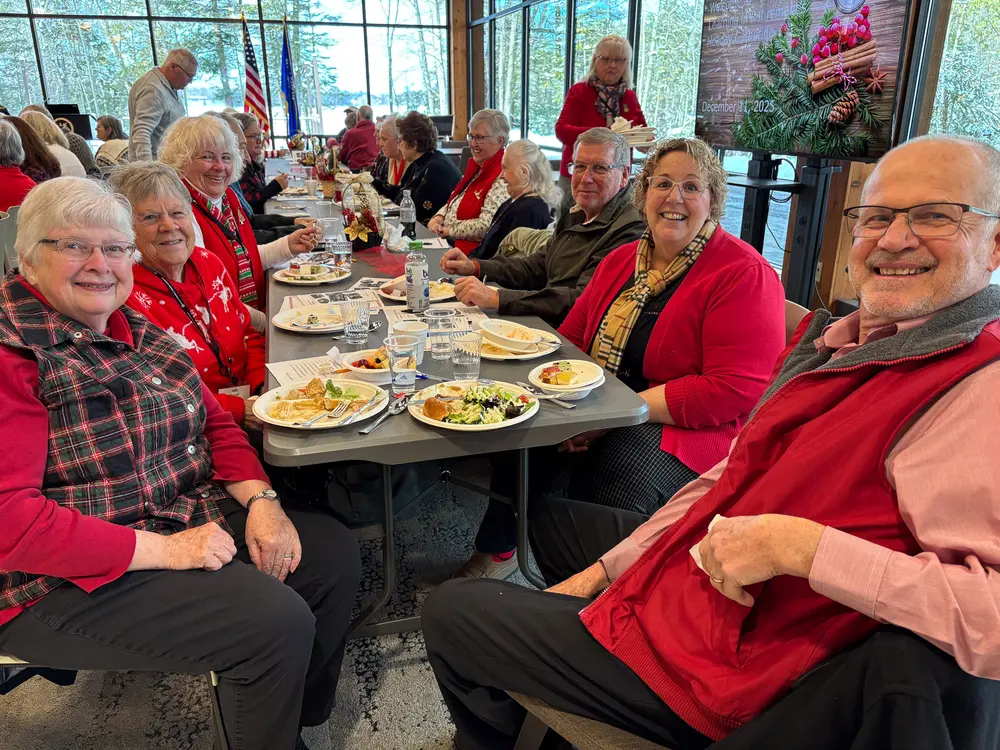 Group of smiling people dining at a long table in a festive setting.
