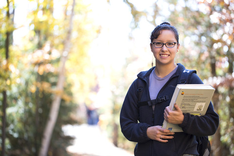 Female student holding books on path going to class