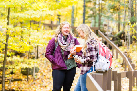 Two girls talking with fall leaves on path