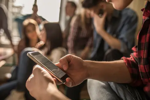 Student in a crowd holding cell phone