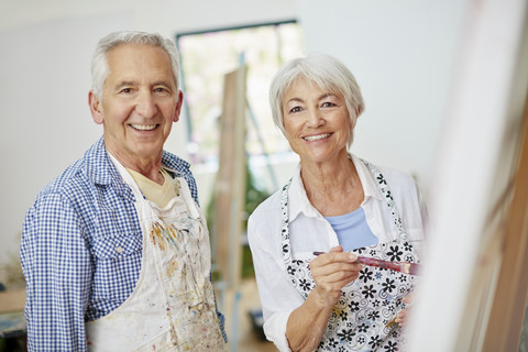 elderly couple painting a picture indoors