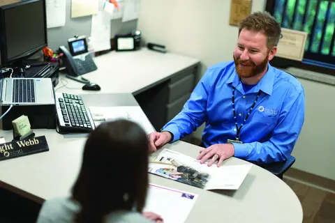 Admissions rep working with student at desk