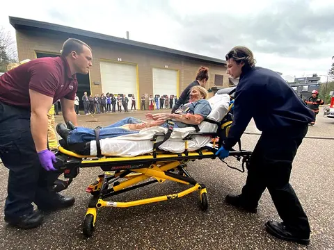 burn victim on stretcher with two emts helping wheel the patient