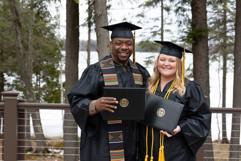 male and female graduates standing outside holding diplomas