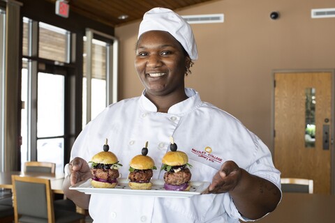 culinary student holding a plate of slider burgers
