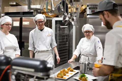 Instructor Chef Mitch working with a group of culinary students in the kitchen