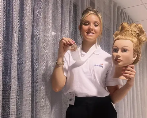 Rachael Reilly, a cosmetology student, holding her bronze medal and mannequin head with an elegant up-do.