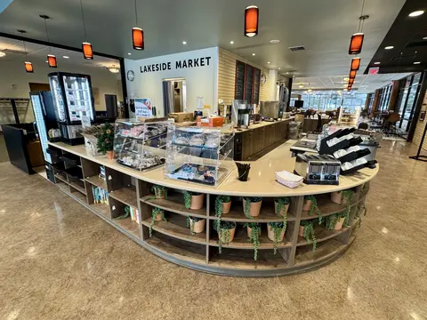 Modern cafe interior with wooden shelves and food displays.