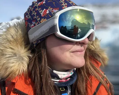 A woman in a winter coat, hat, and snow goggles.